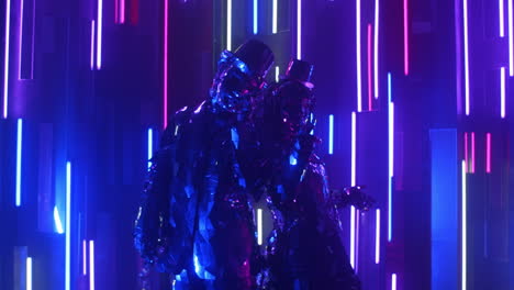 Zwei-Robotertänzer-In-Glitzernden-Kostümen-Tanzen-Vor-Einer-Neonwand-Und-Kommen-Einander-Näher.
